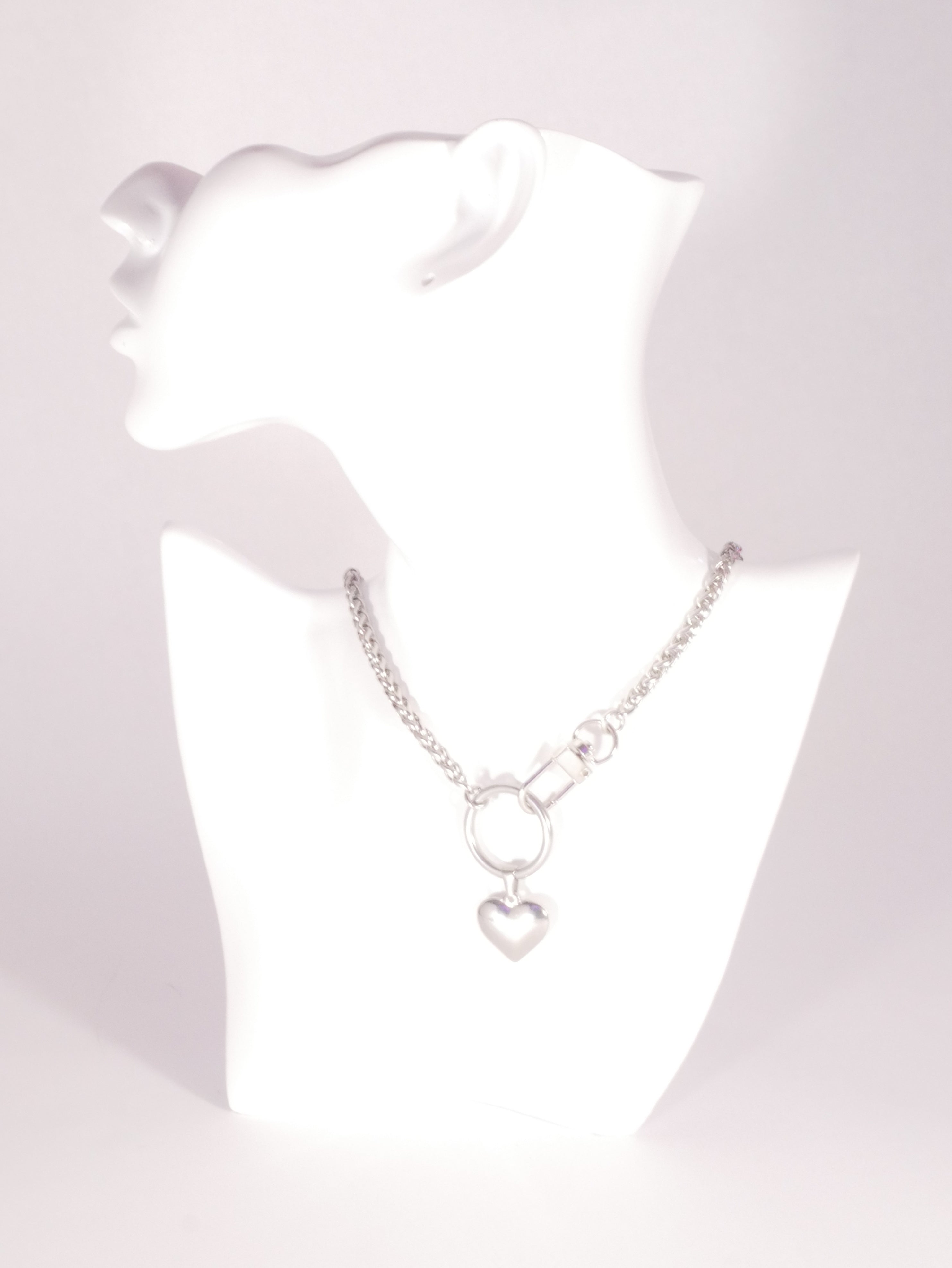 Silver necklace with heart pendants on a white mannequin bust.