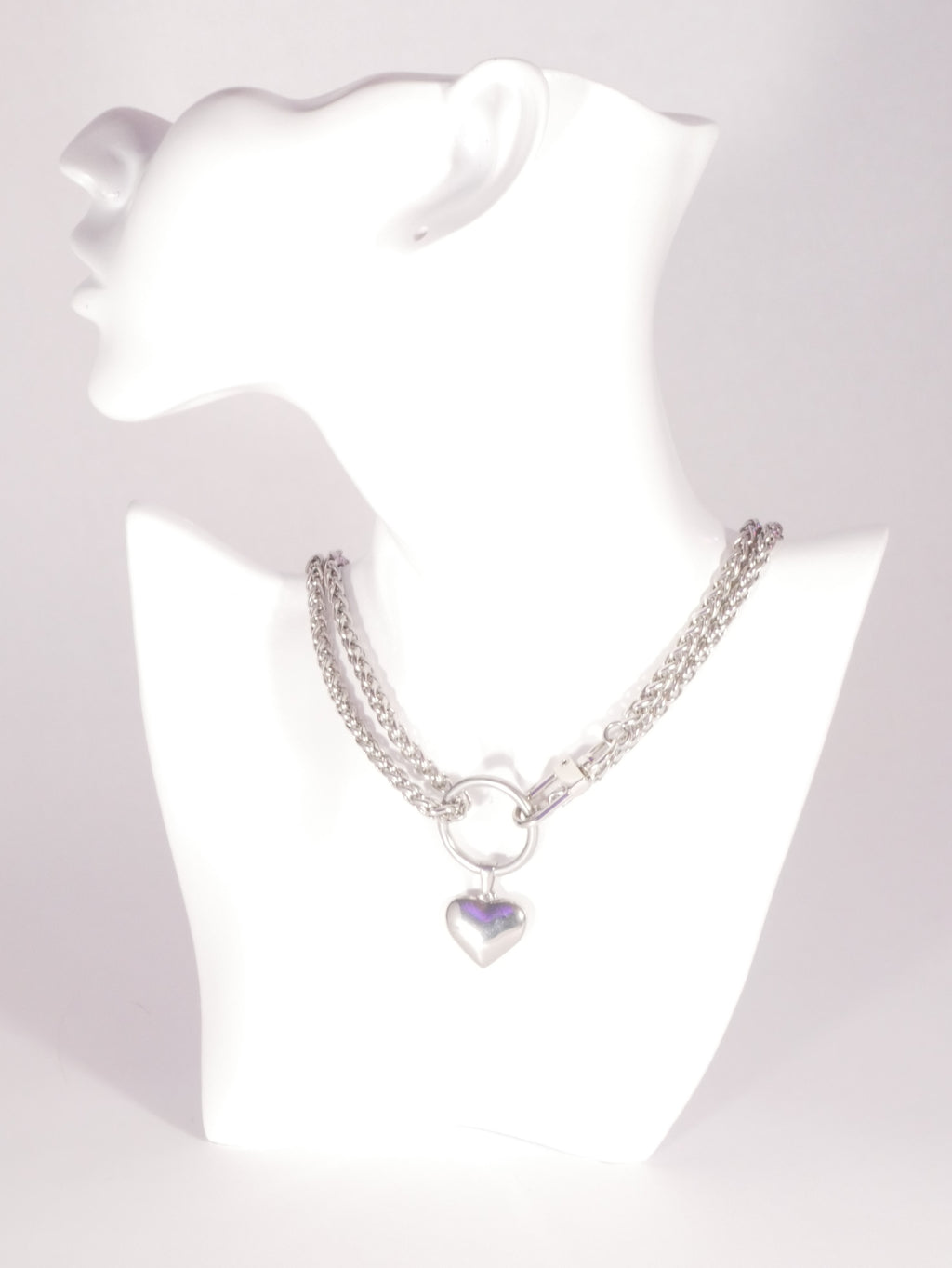 Silver bracelet with a heart-shaped charm on a white mannequin.
