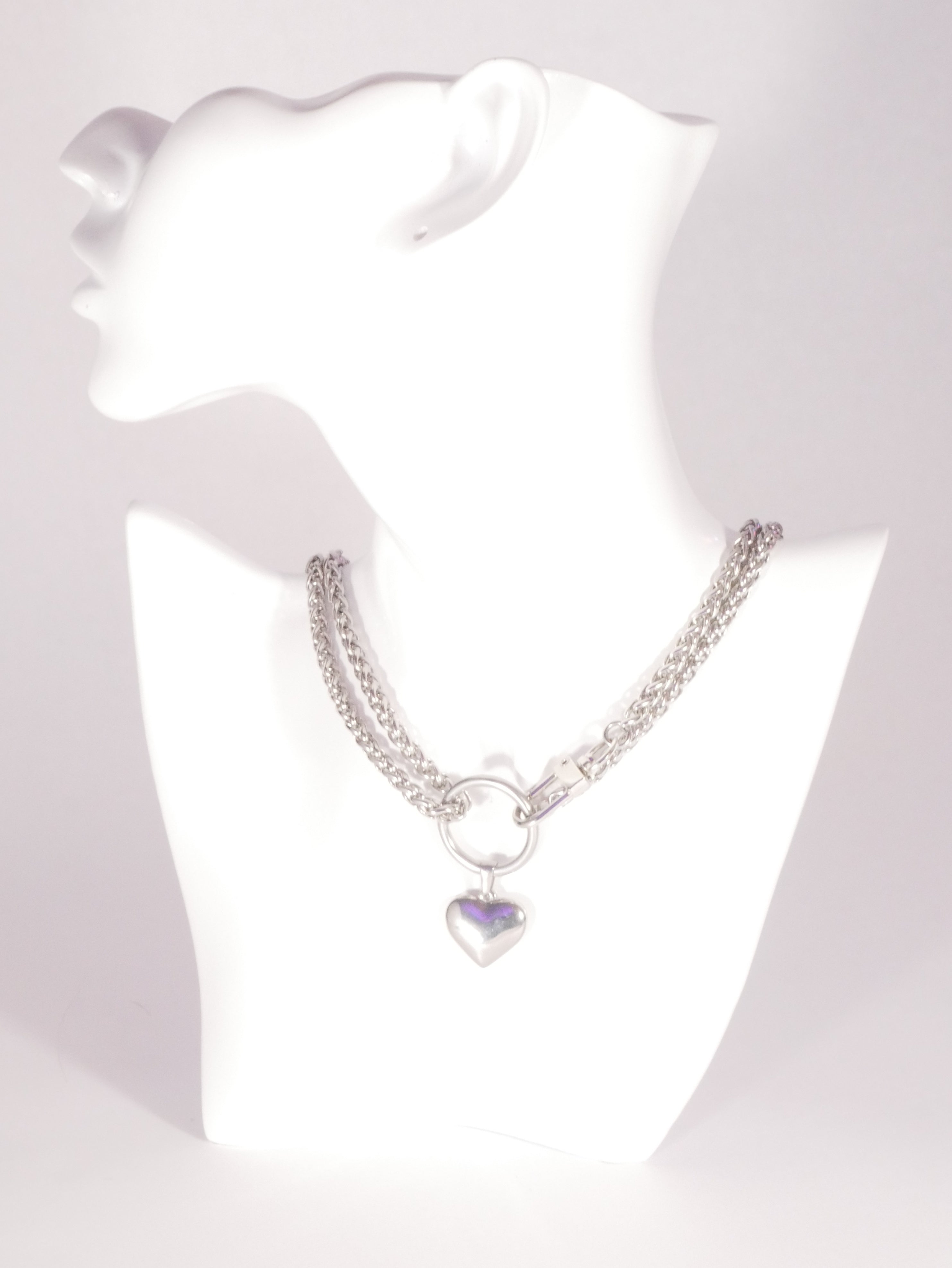 Silver bracelet with a heart-shaped charm on a white mannequin.