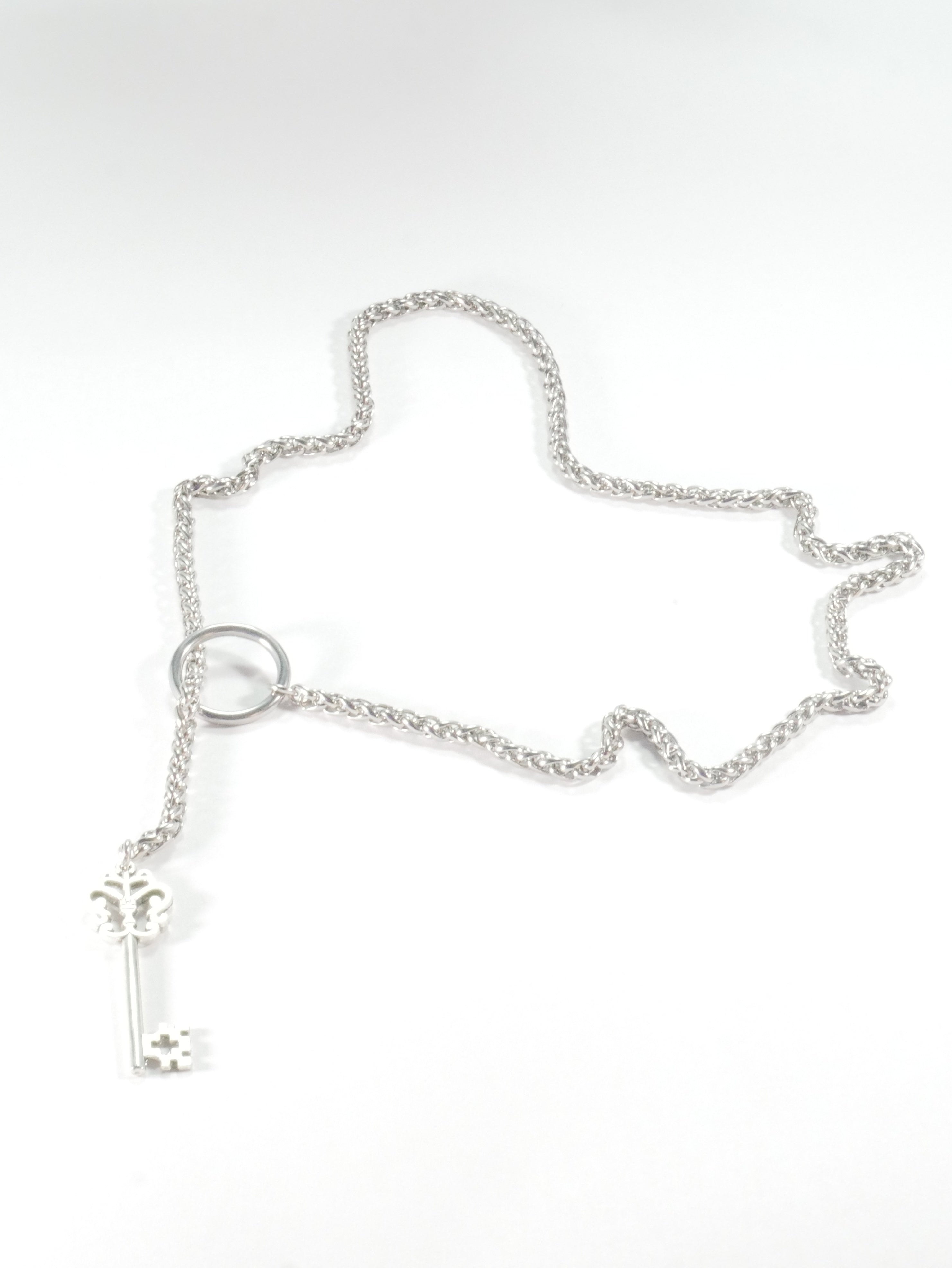 Silver chain bracelet with a key charm on a white background
