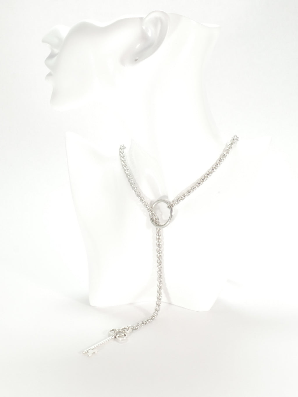 Silver necklace on a white mannequin bust with a white background