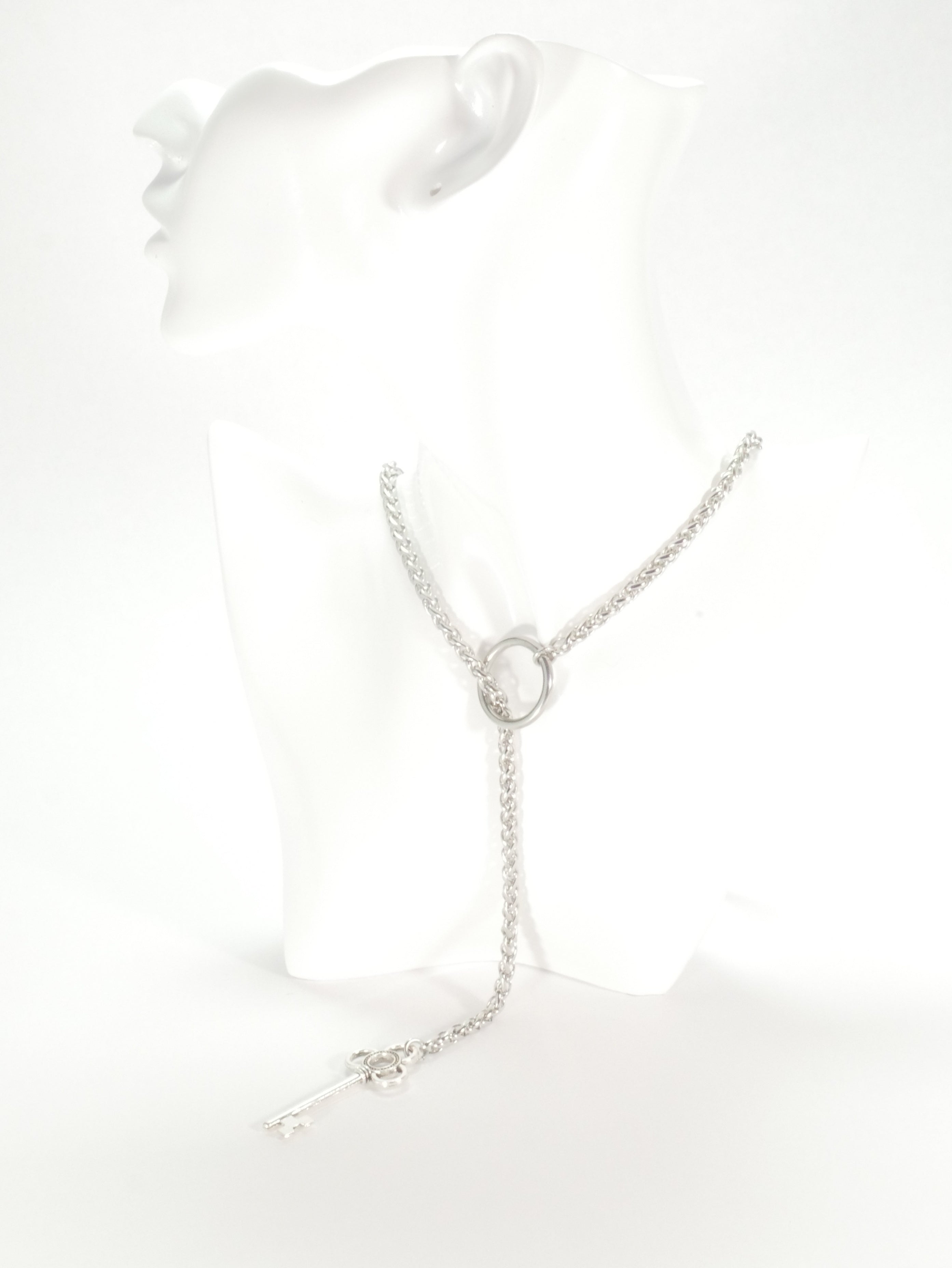 Silver necklace on a white mannequin bust with a white background