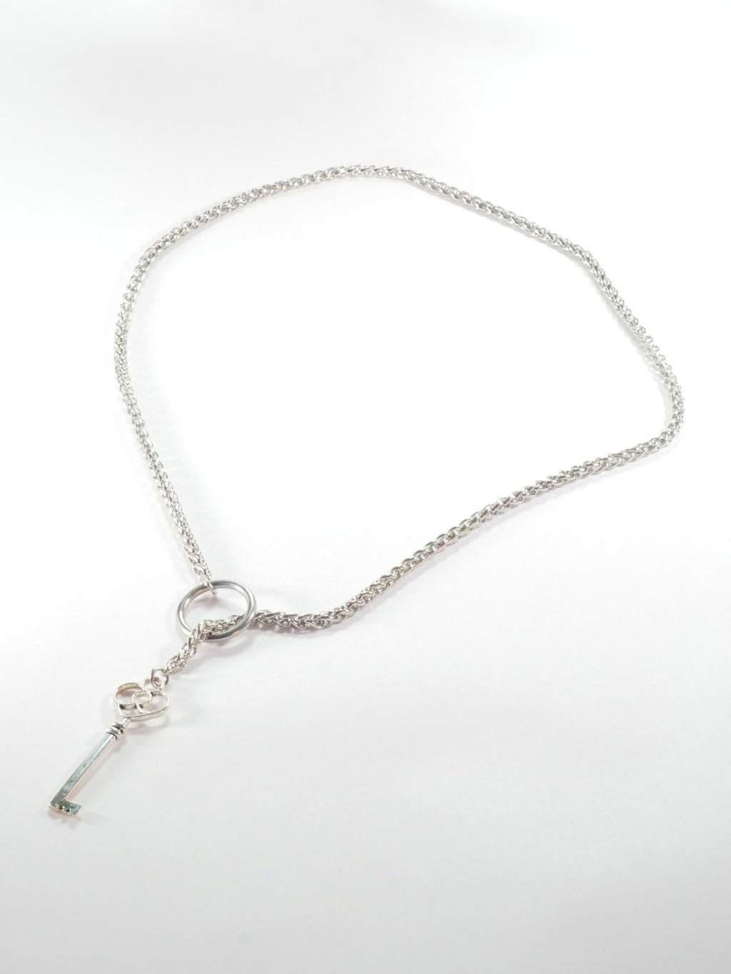 Silver necklace with a key pendant on a white background