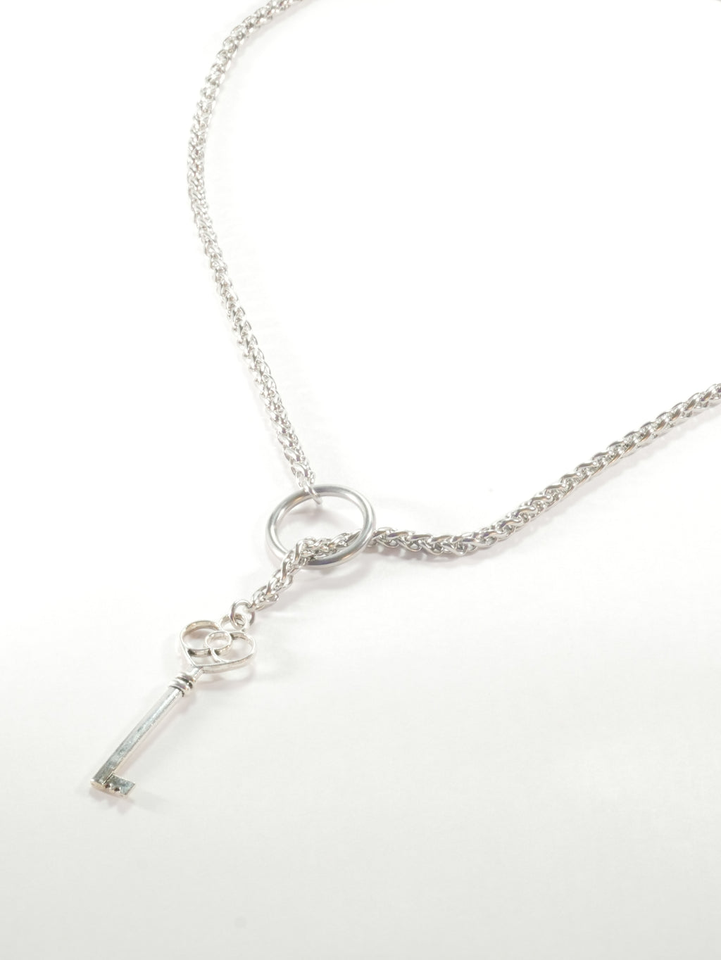 Silver necklace with a key pendant on a white background