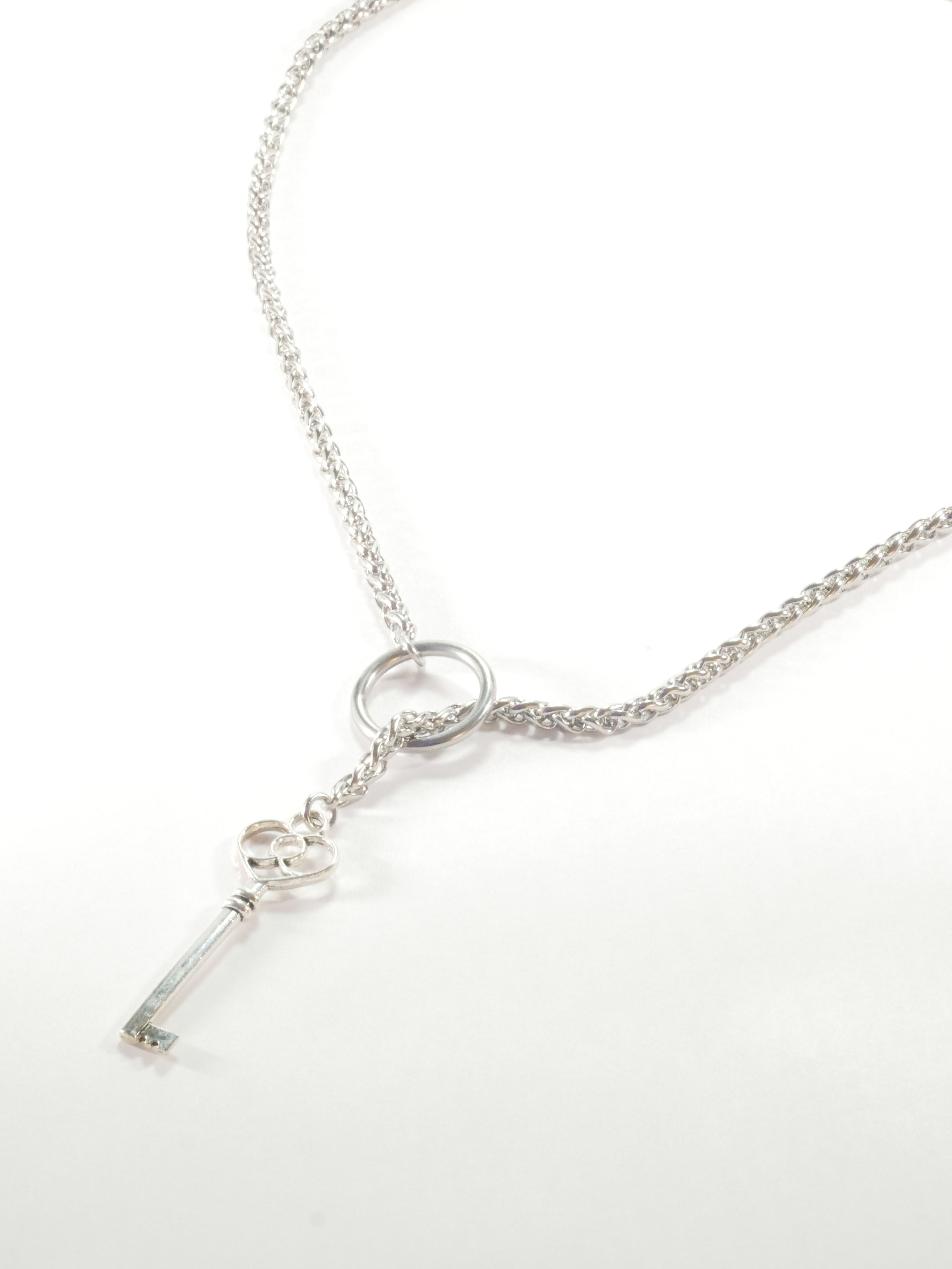 Silver necklace with a key pendant on a white background