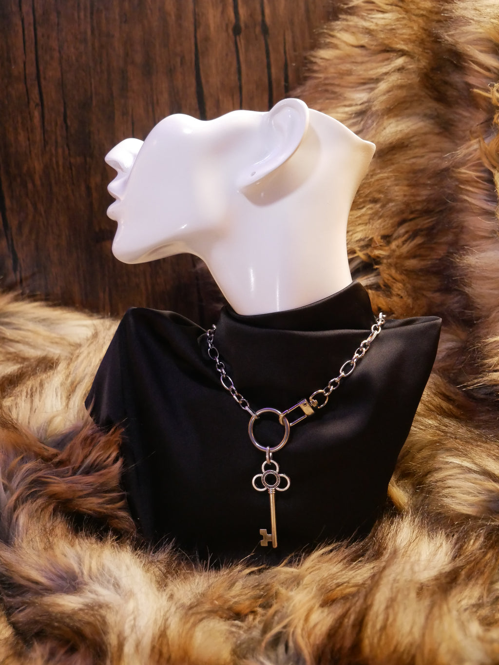 silver chain necklace on a mannequin wearing a black satin top sitting on a brown fur