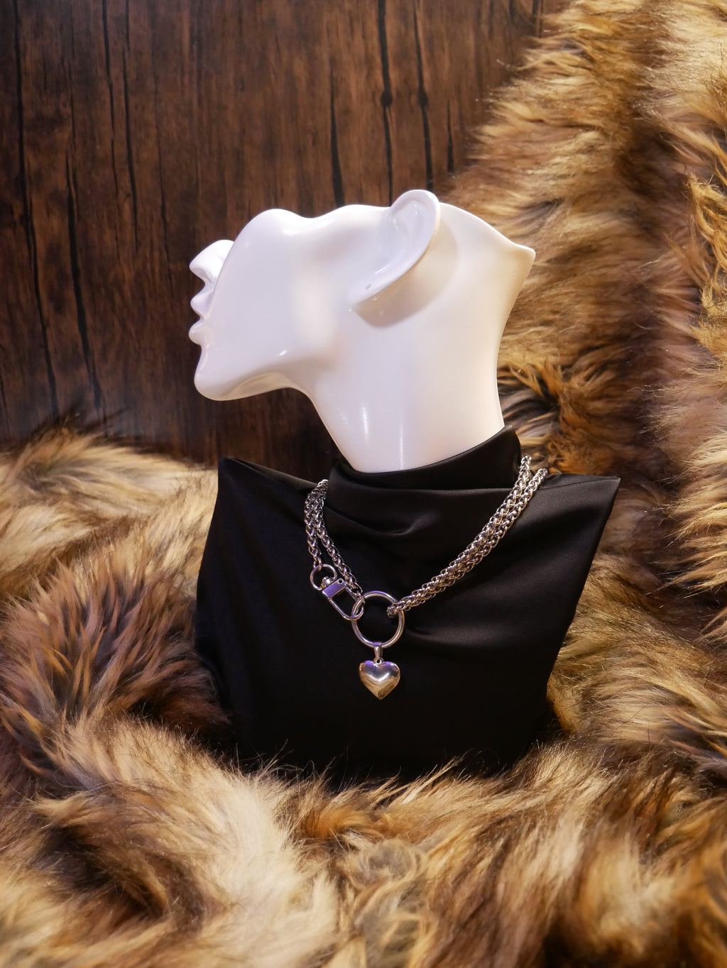 silver chain necklace on a mannequin wearing a black satin top sitting on a brown fur