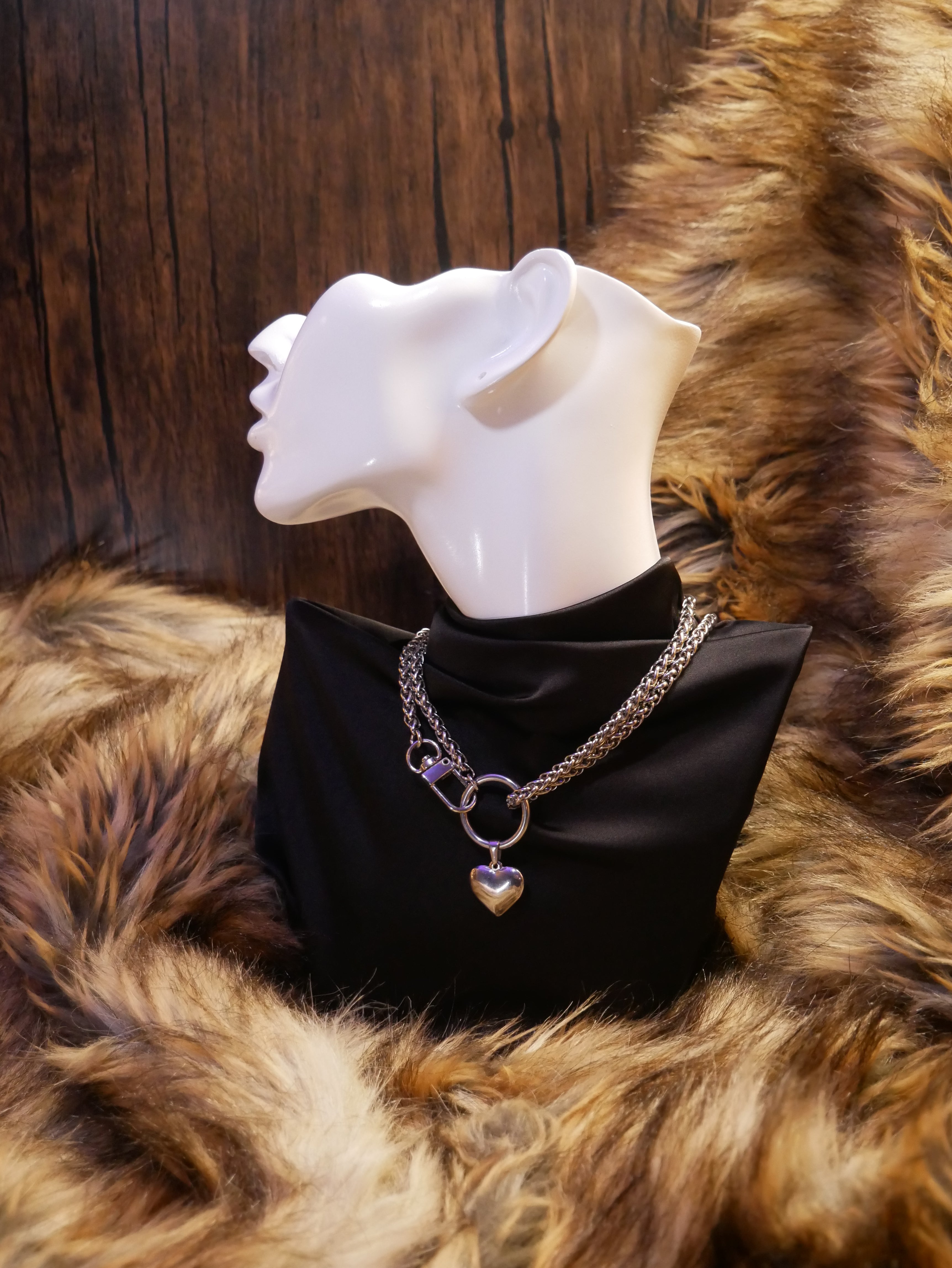 silver chain necklace on a mannequin wearing a black satin top sitting on a brown fur