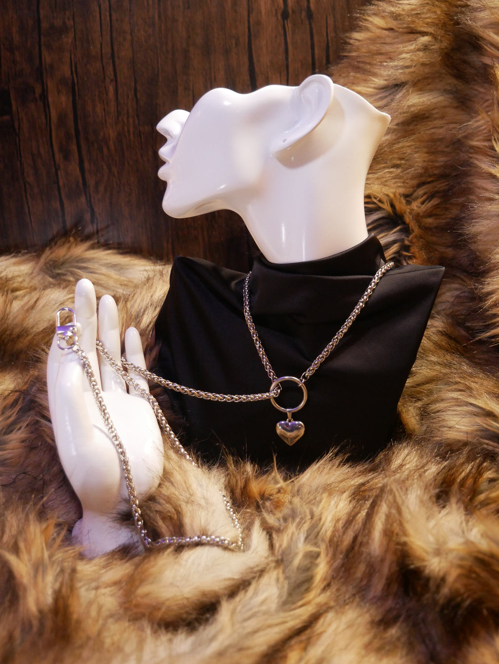 silver chain necklace on a mannequin wearing a black satin top sitting on a brown fur