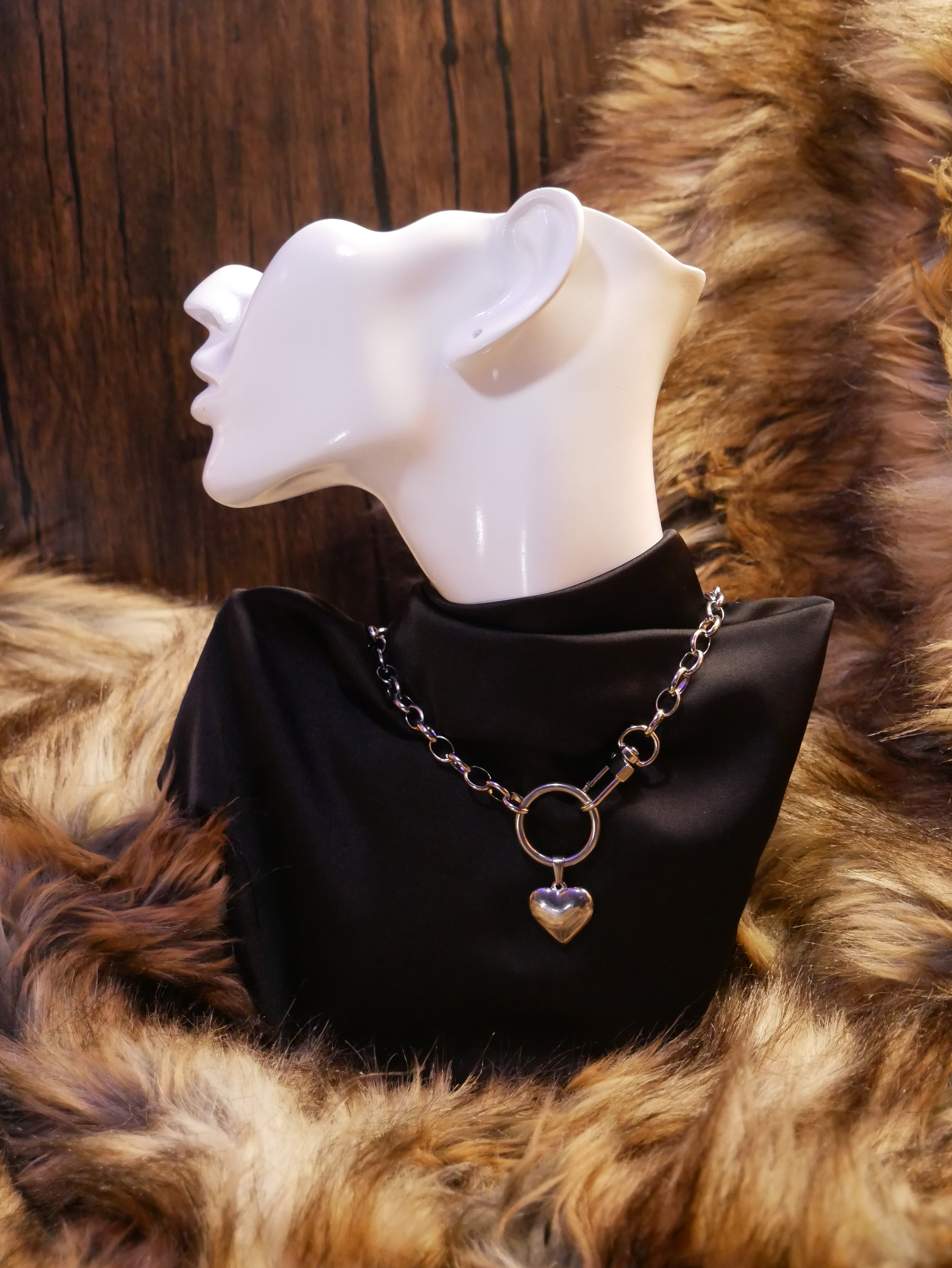 silver chain necklace on a mannequin wearing a black satin top sitting on a brown fur