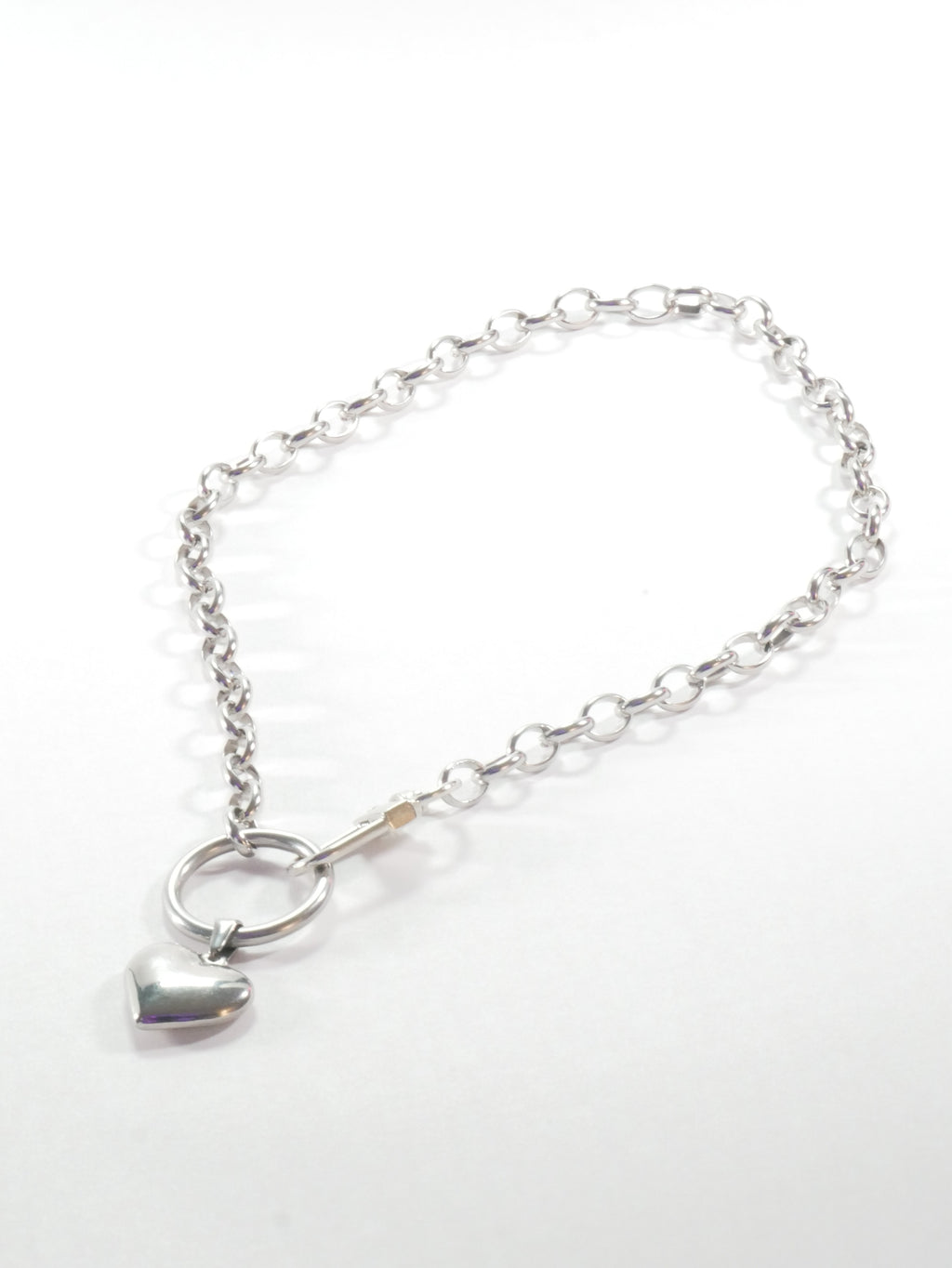 Silver bracelet with a heart charm on a white background