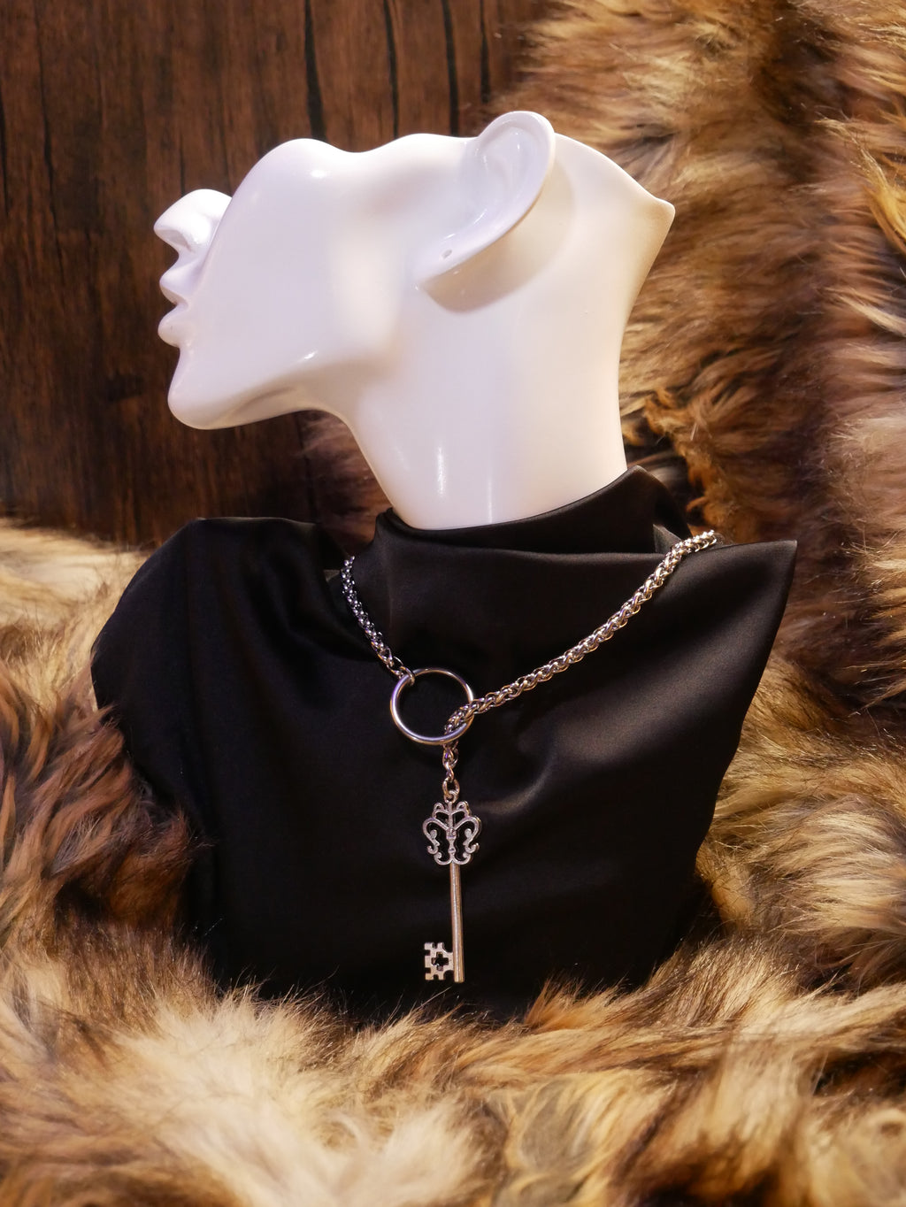 silver chain necklace on a mannequin wearing a black satin top sitting on a brown fur
