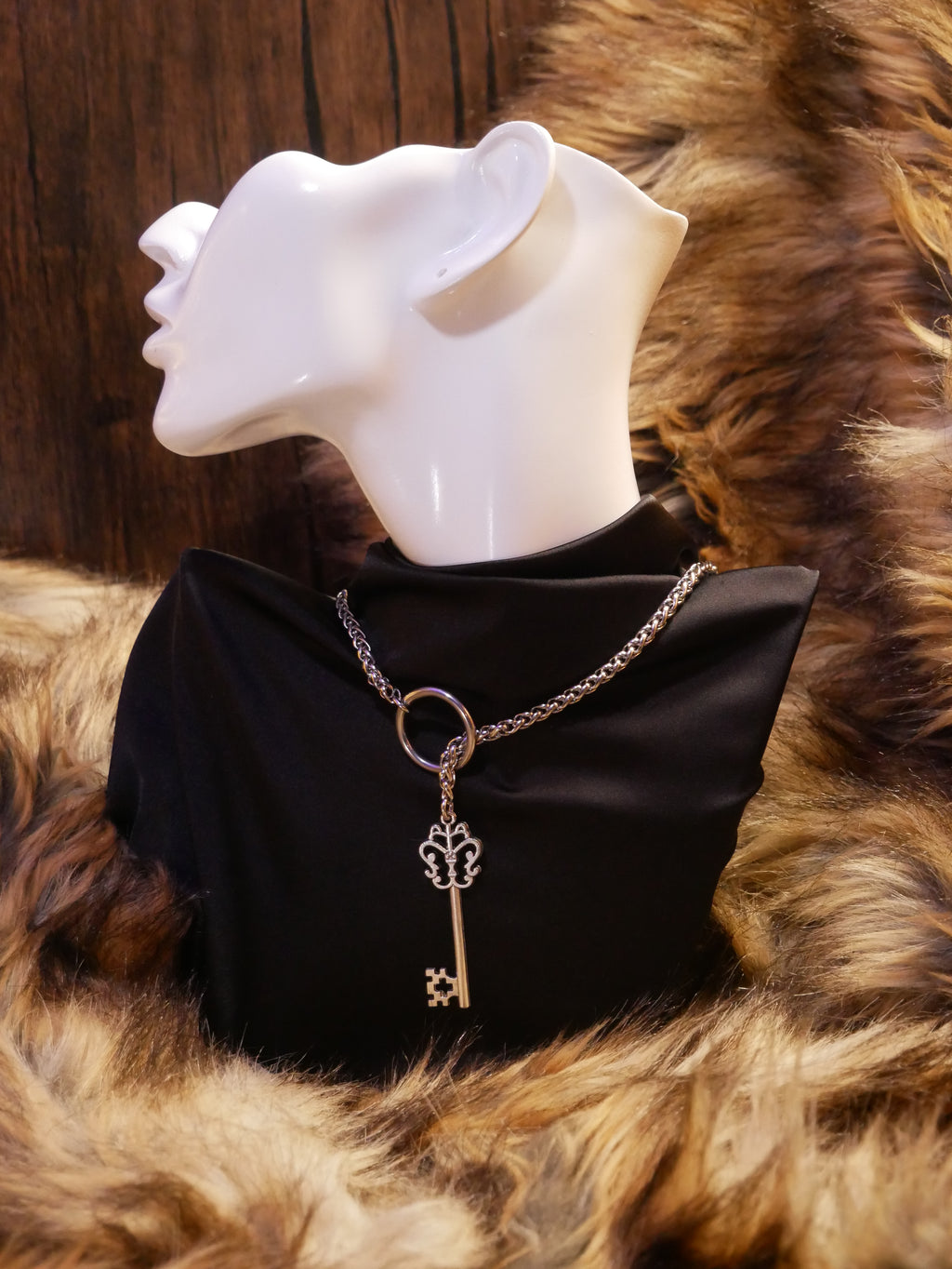 silver chain necklace on a mannequin wearing a black satin top sitting on a brown fur