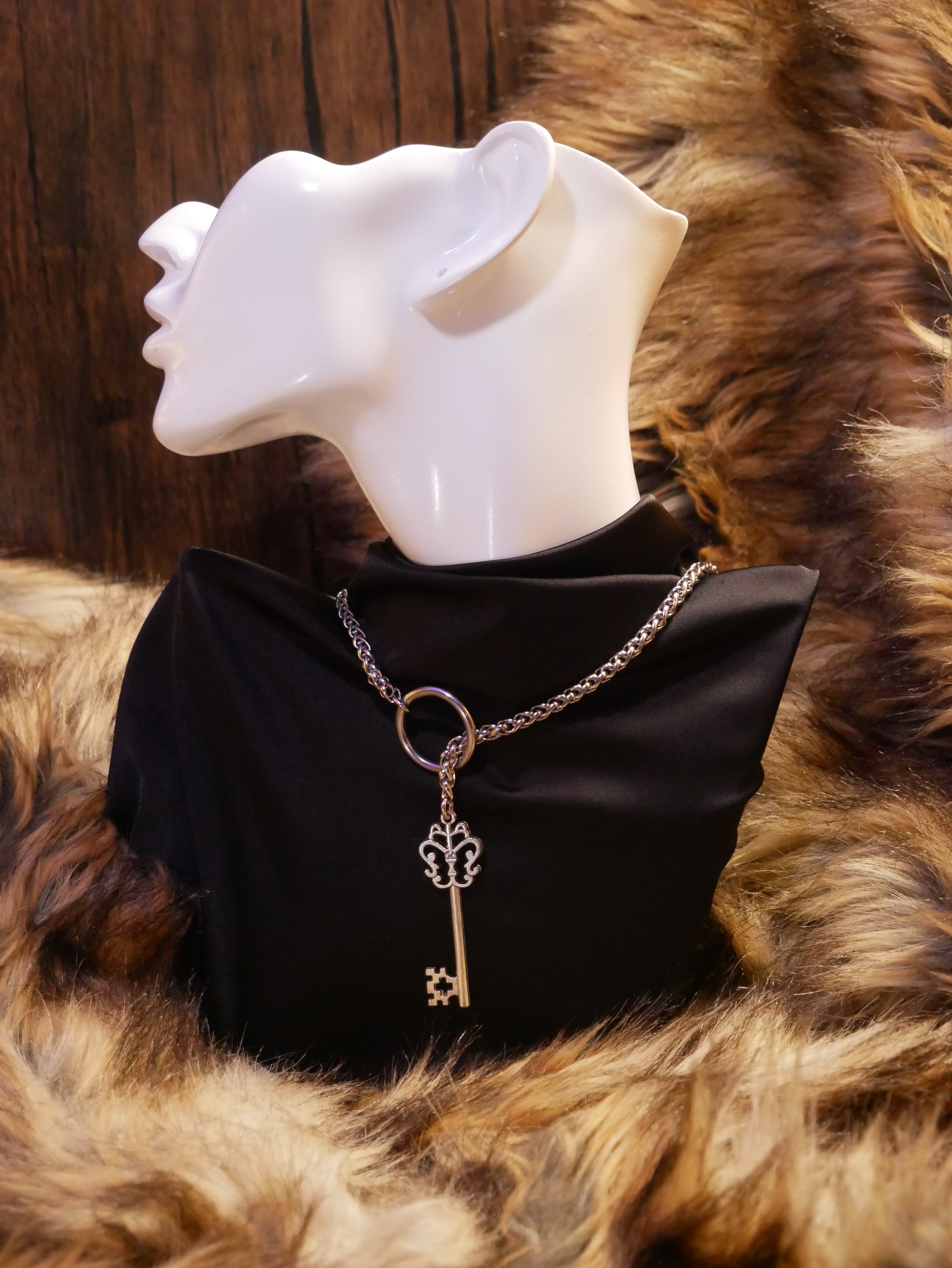 silver chain necklace on a mannequin wearing a black satin top sitting on a brown fur