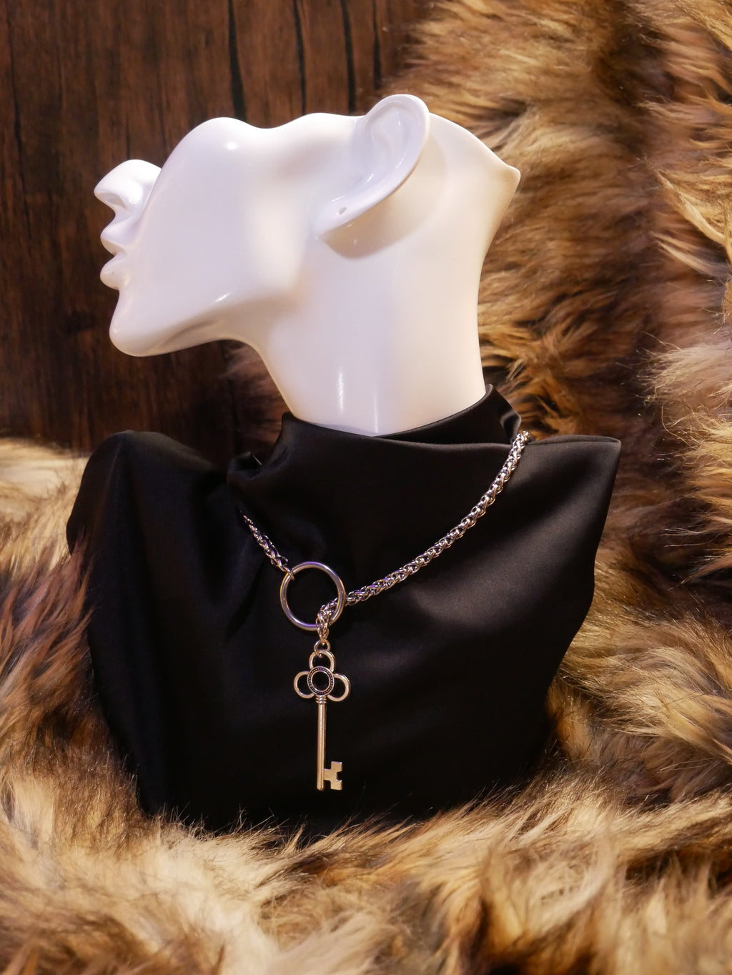 silver chain necklace on a mannequin wearing a black satin top sitting on a brown fur