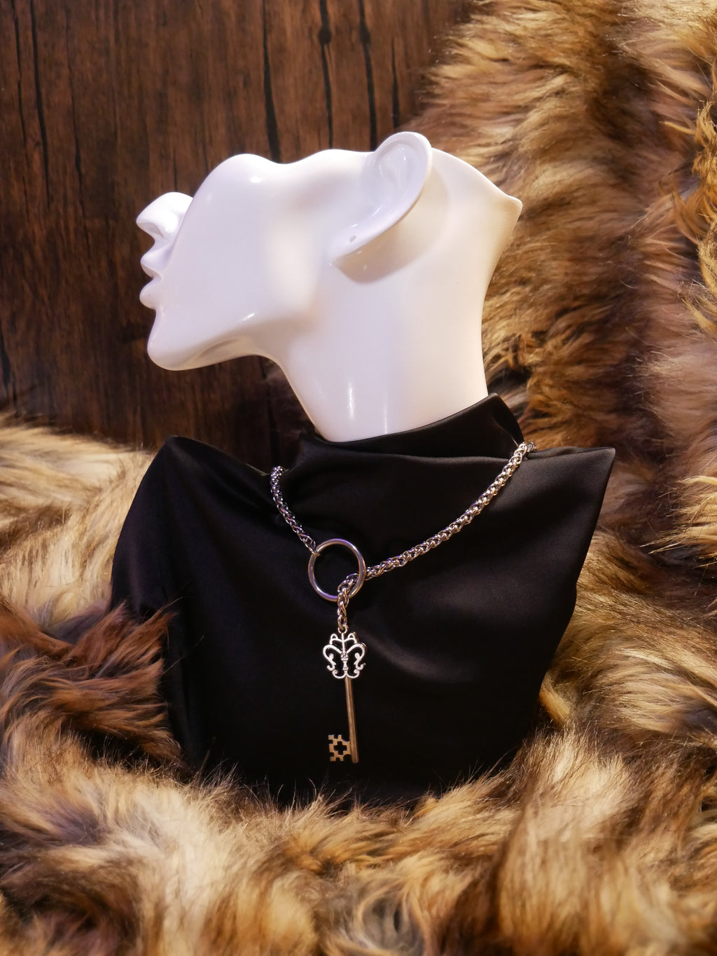 silver chain necklace on a mannequin wearing a black satin top sitting on a brown fur