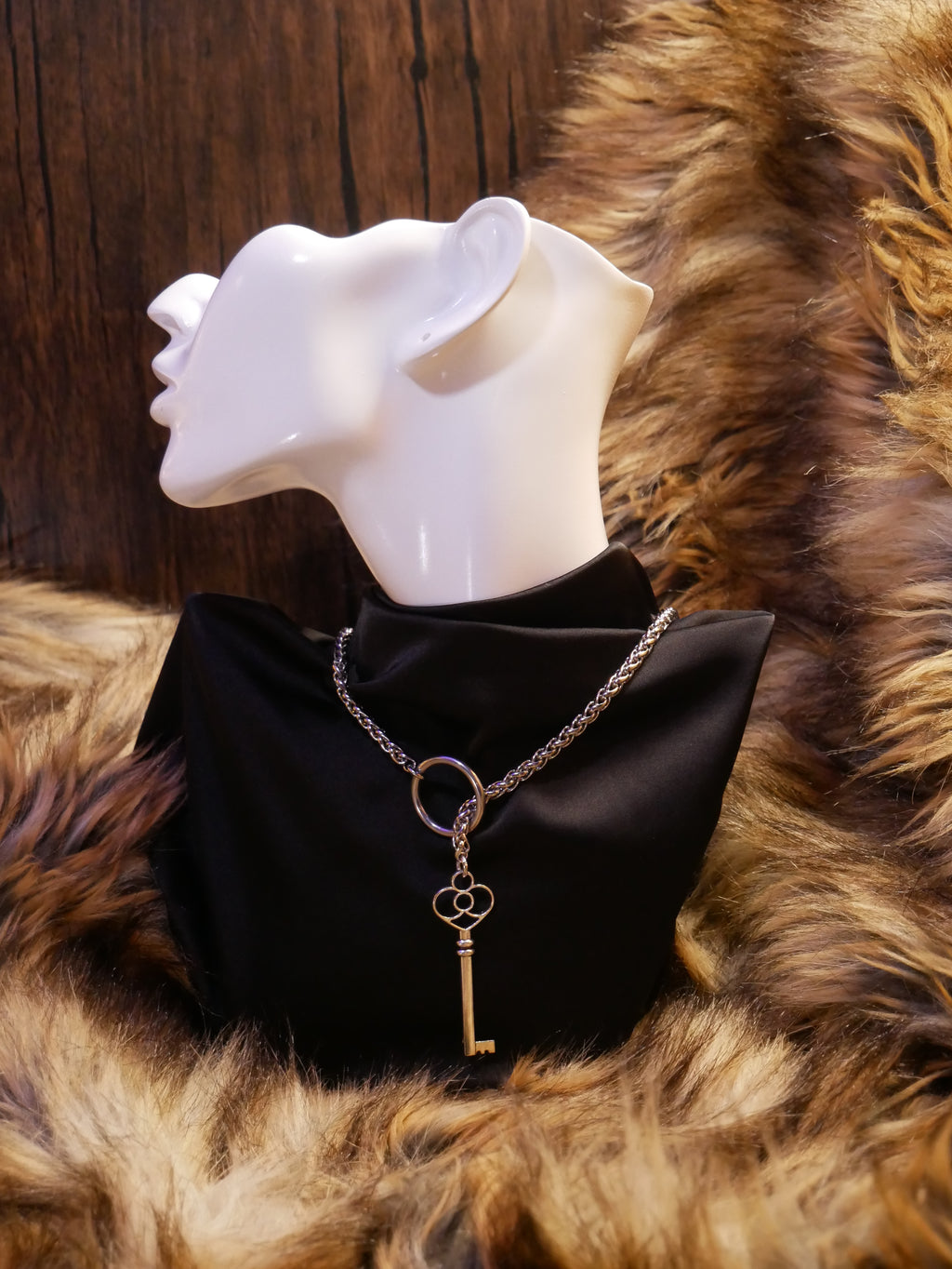 silver chain necklace on a mannequin wearing a black satin top sitting on a brown fur
