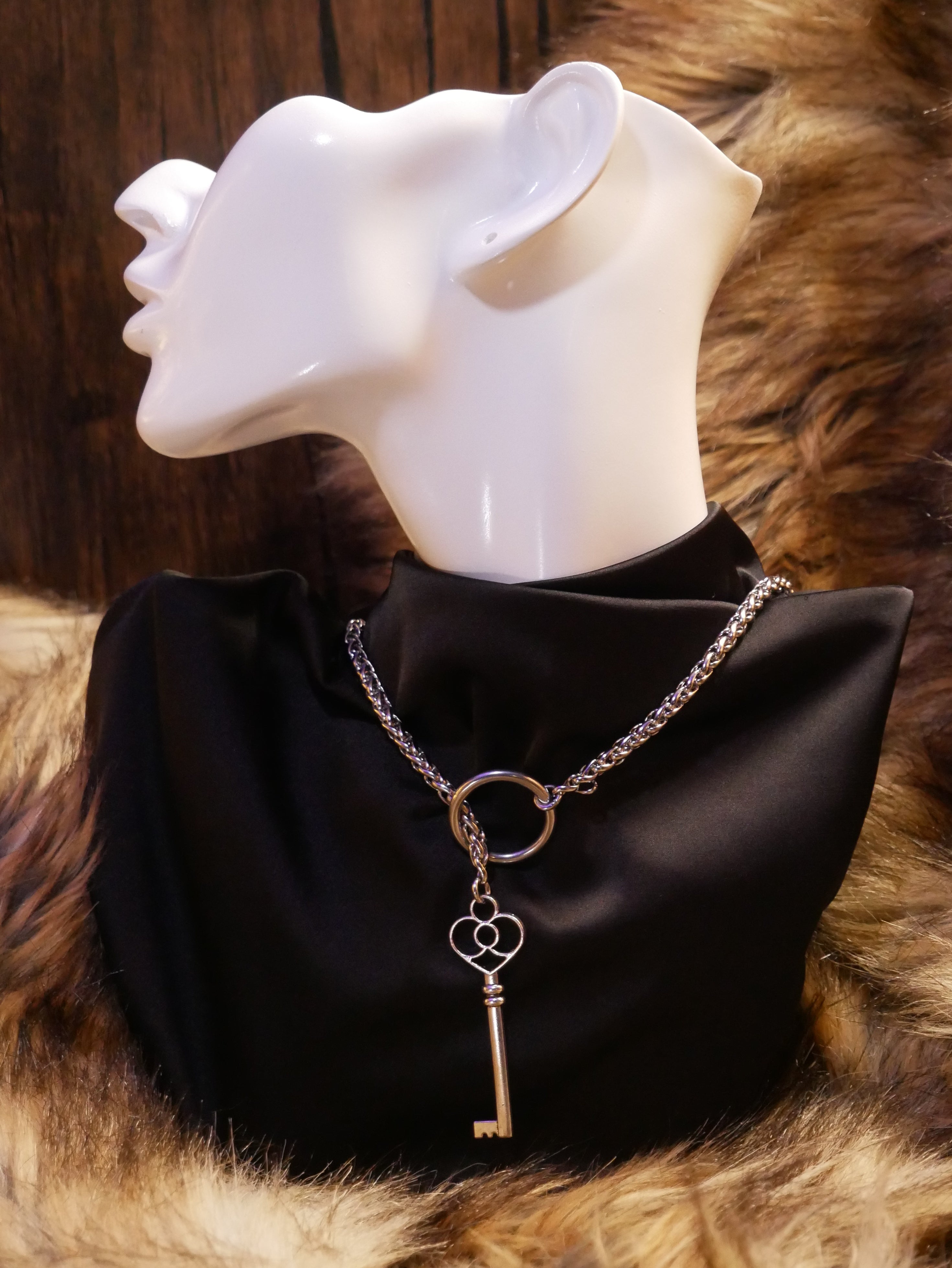 silver chain necklace on a mannequin wearing a black satin top sitting on a brown fur