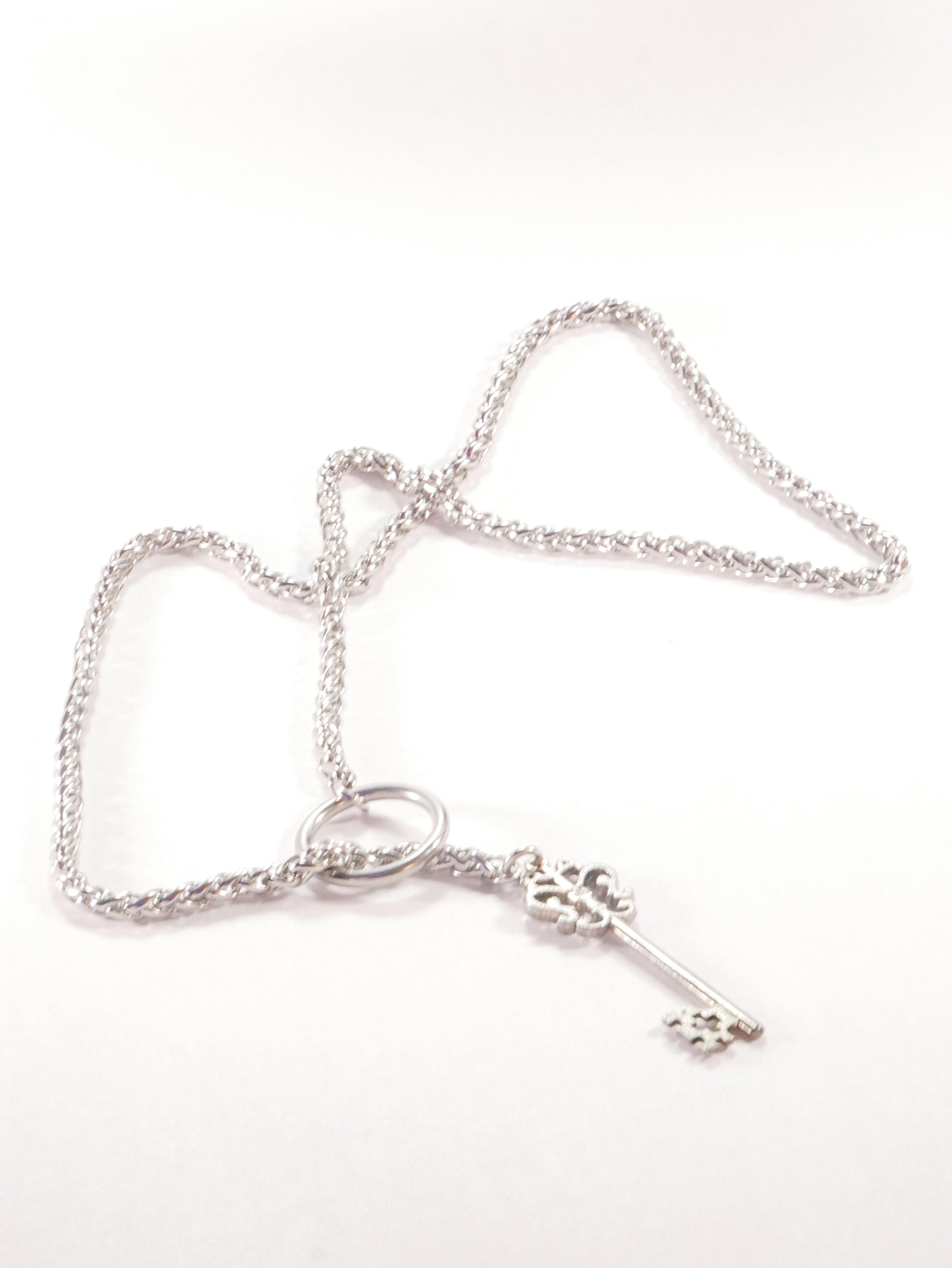 Silver bracelet with a key charm on a white background