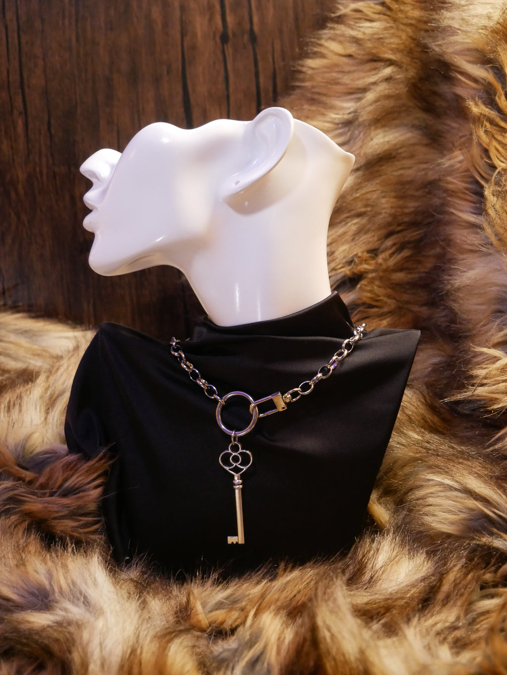 silver chain necklace on a mannequin wearing a black satin top sitting on a brown fur