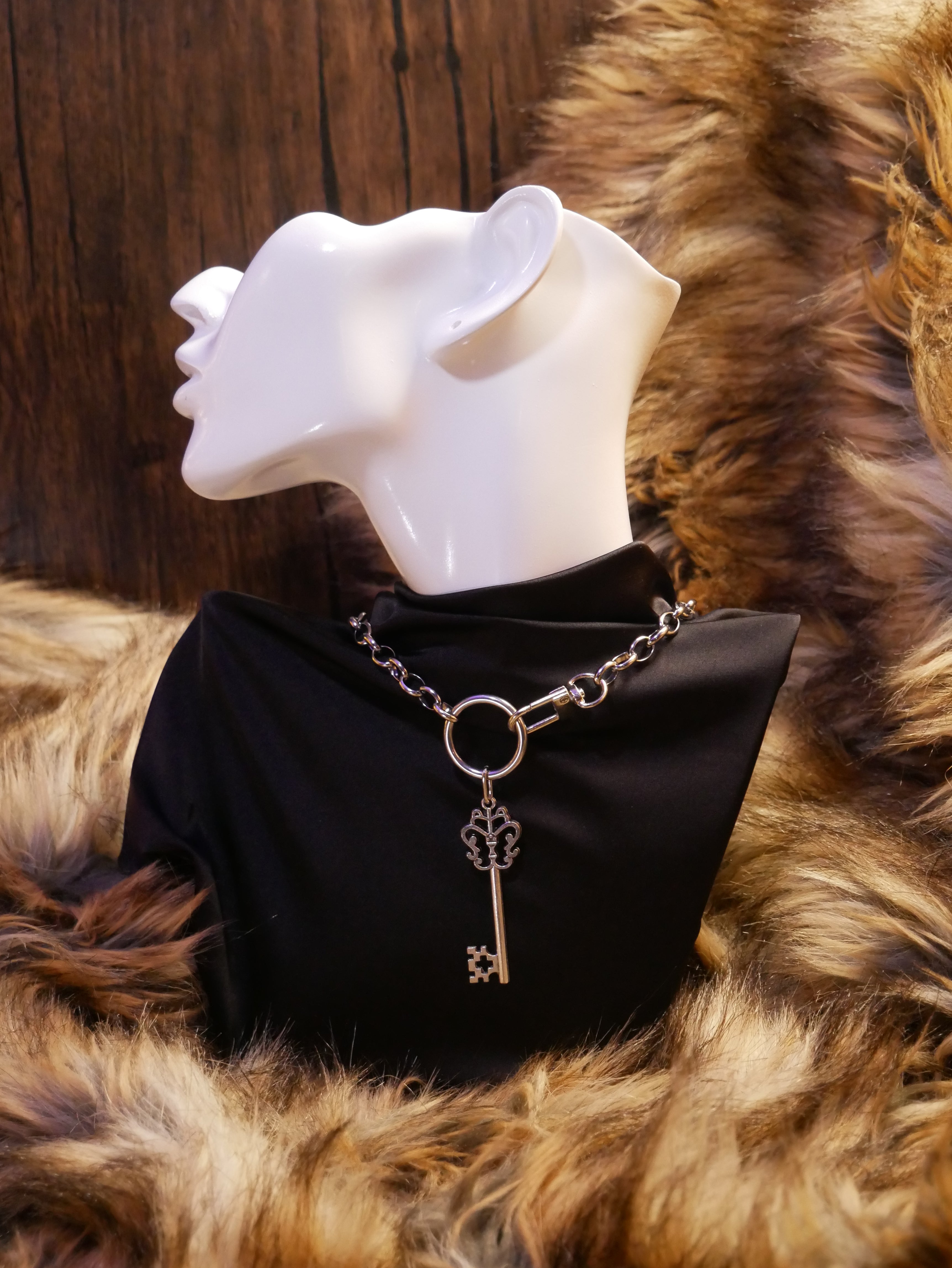 silver chain necklace on a mannequin wearing a black satin top sitting on a brown fur