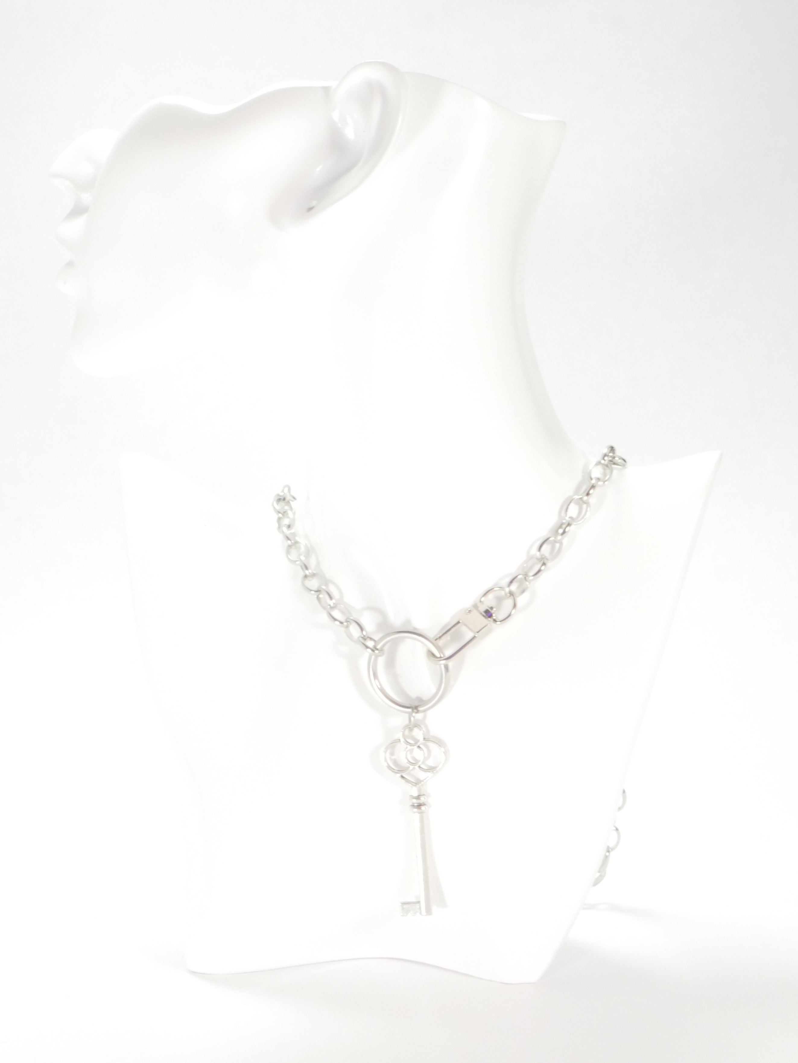 Silver necklace with a key pendant on a white background