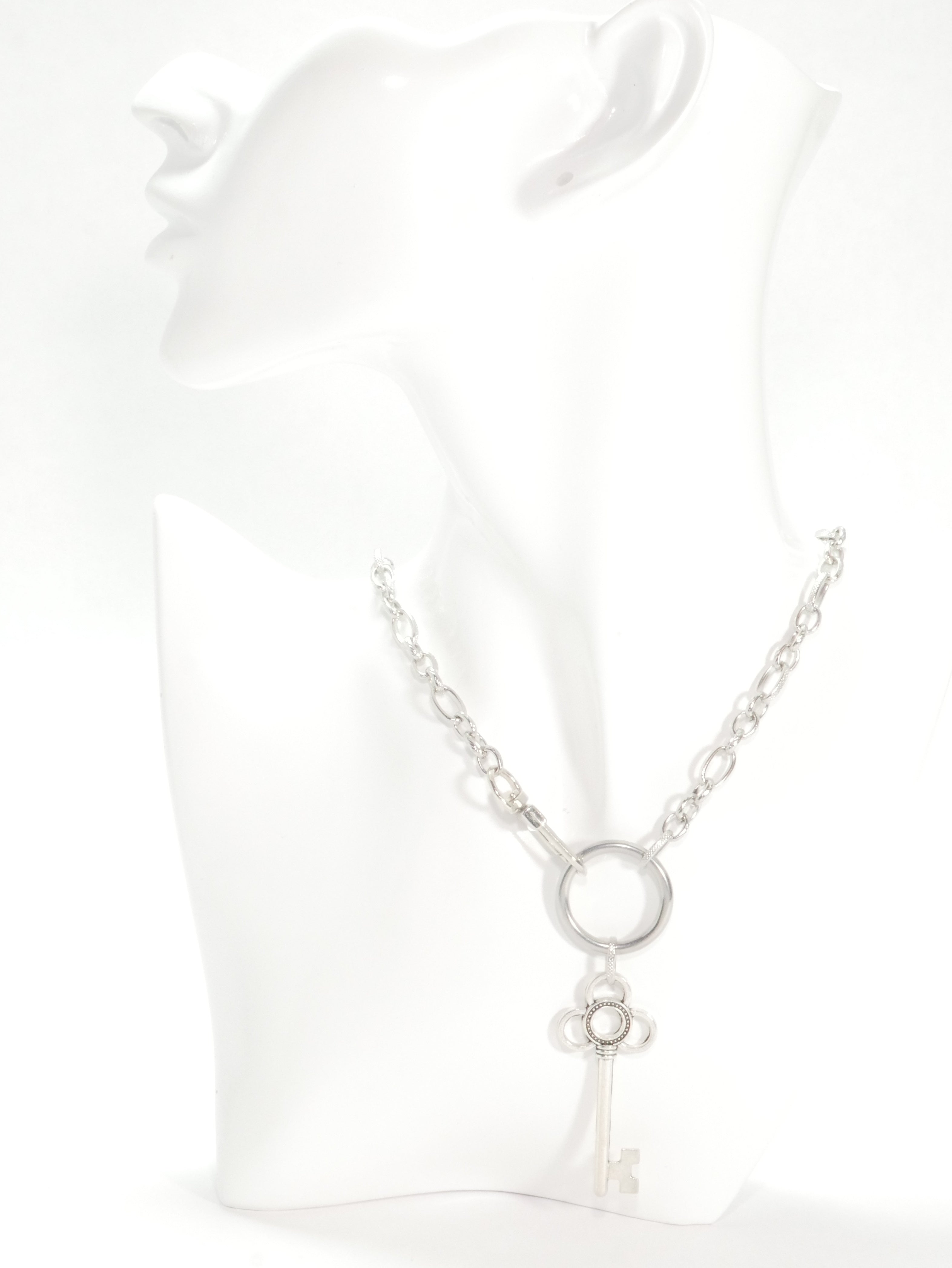 Silver necklace with a key pendant on a white background