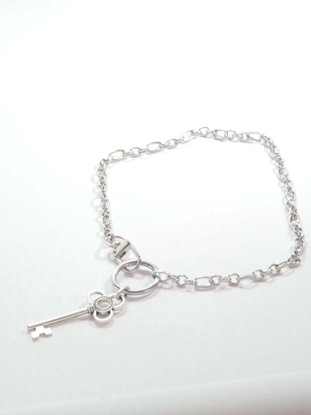 Silver bracelet with a key charm on a white background