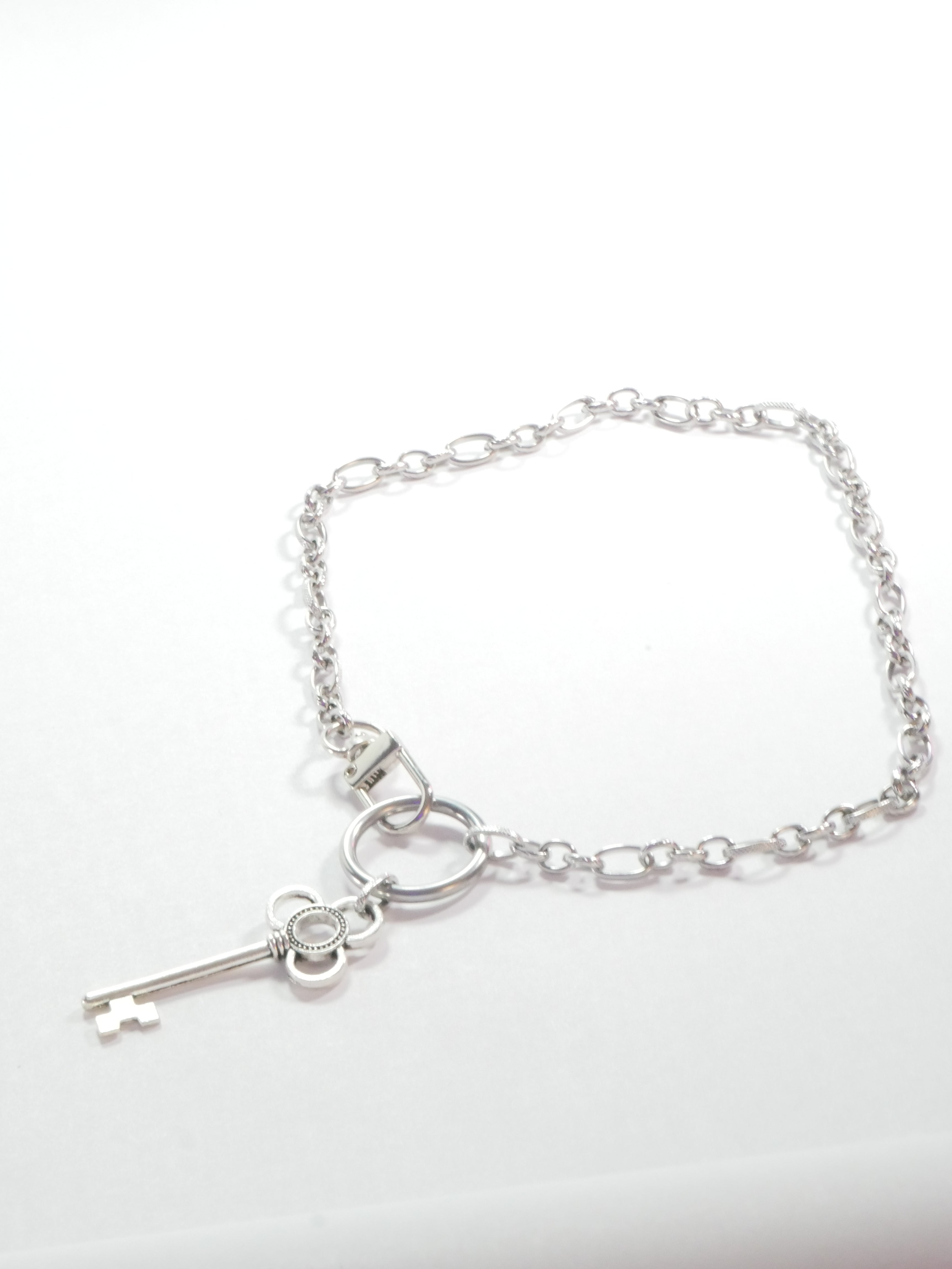 Silver bracelet with a key charm on a white background