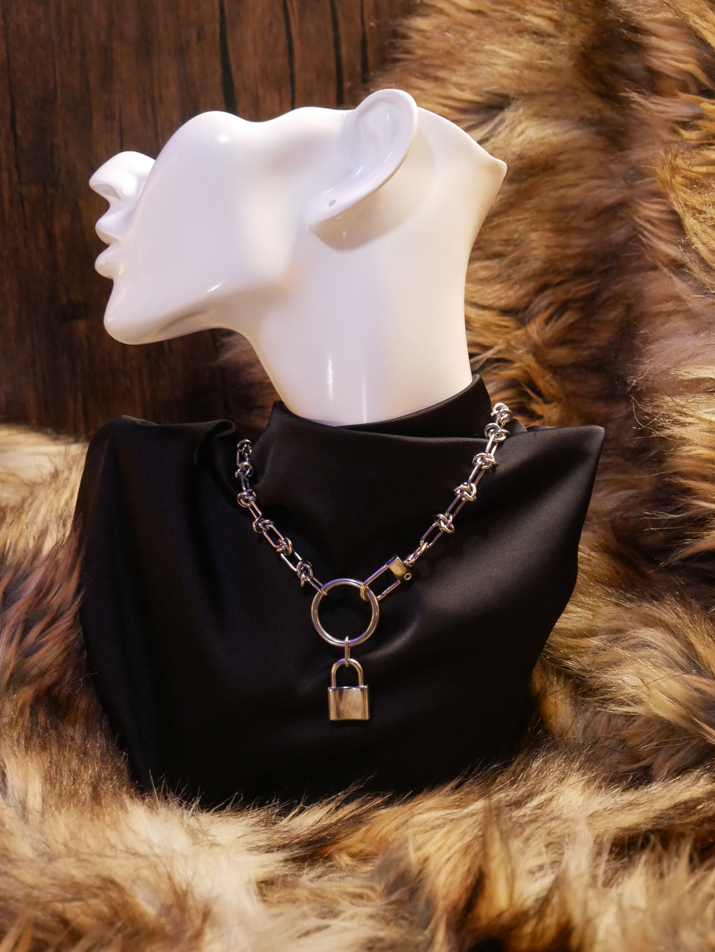 silver chain necklace on a mannequin wearing a black satin top sitting on a brown fur