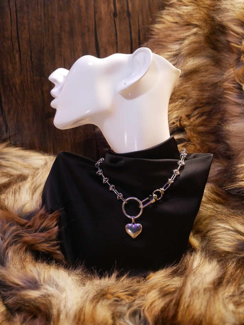 silver chain necklace on a mannequin wearing a black satin top sitting on a brown fur