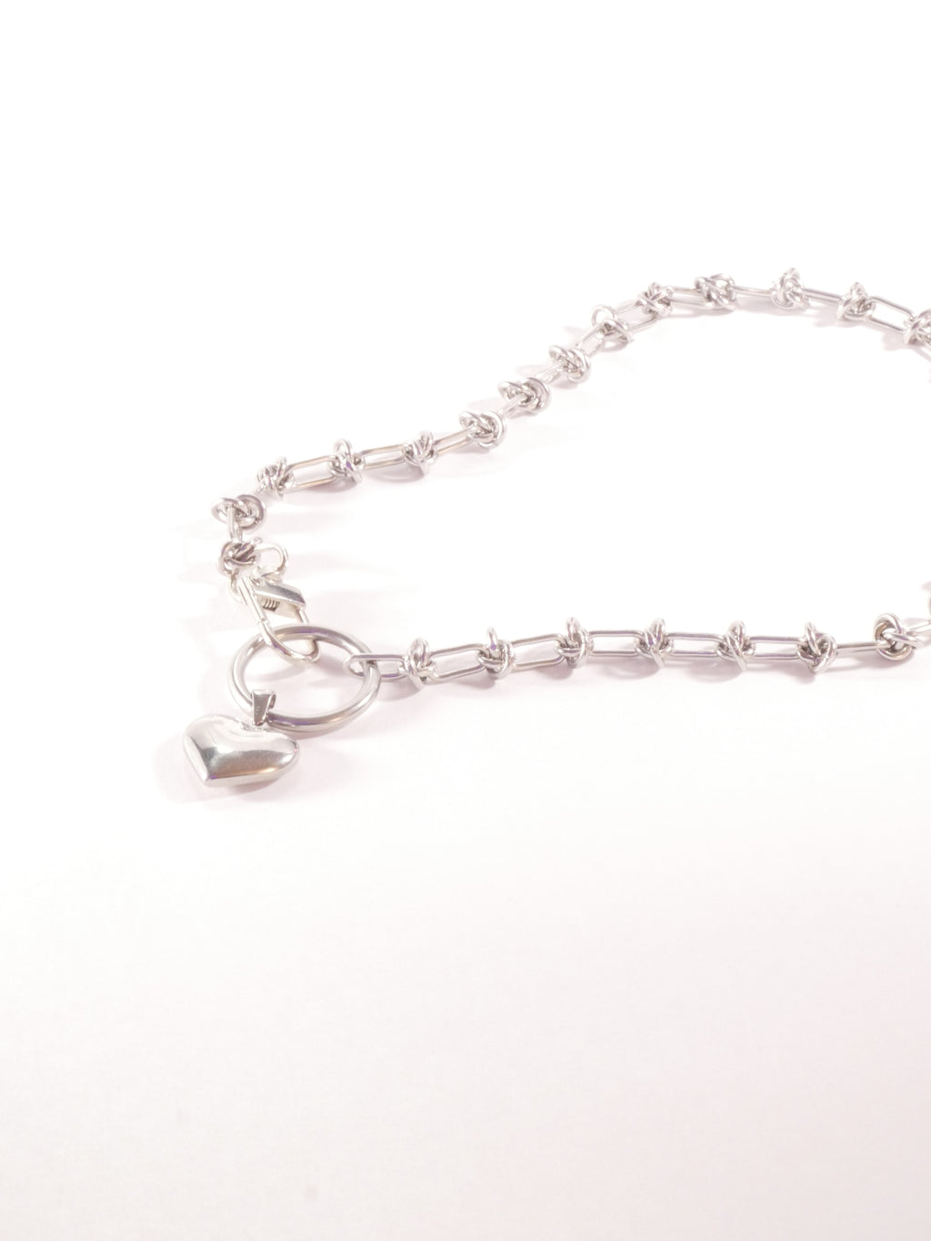Silver necklace with a heart-shaped pendant on a white background
