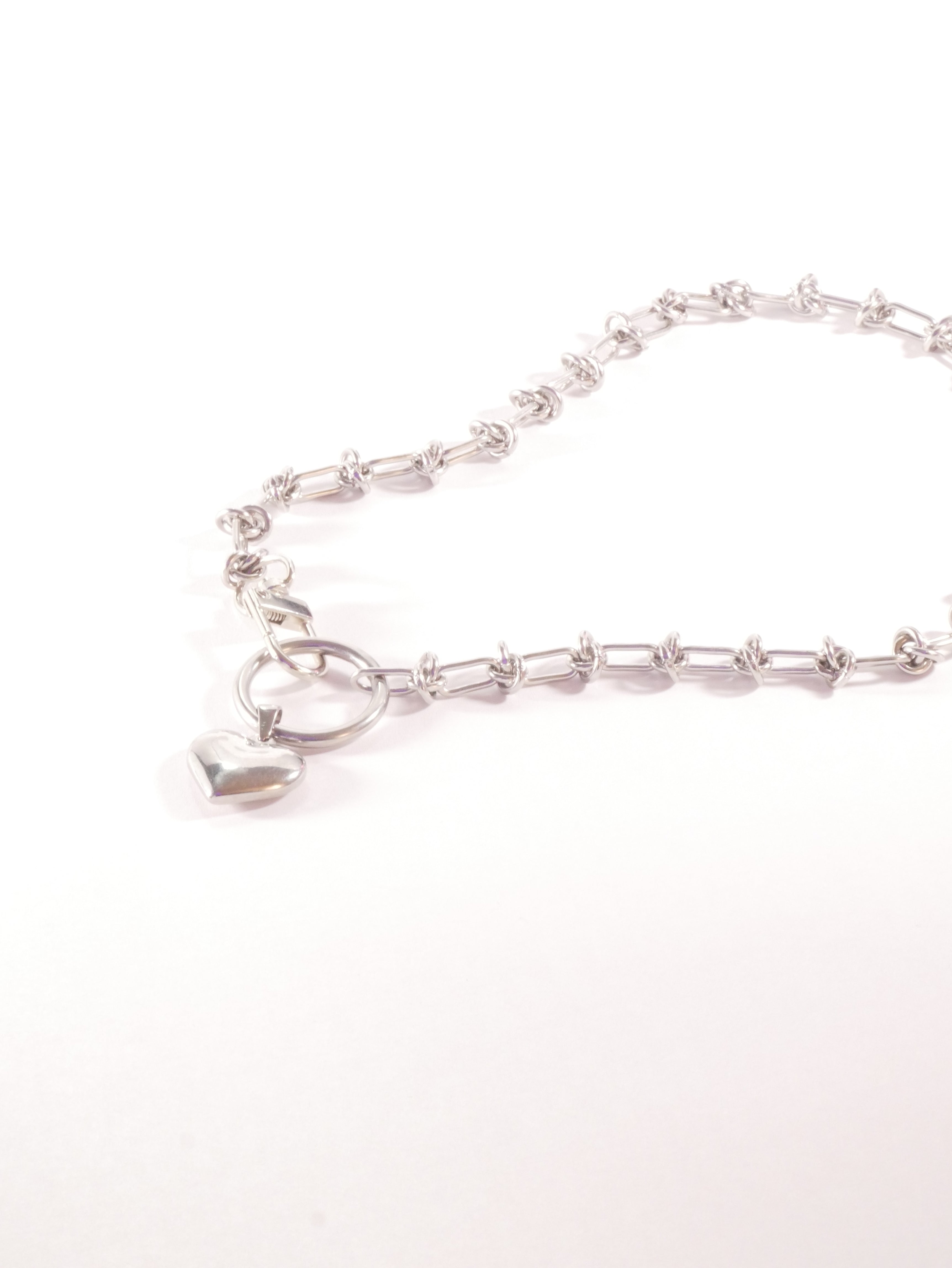 Silver necklace with a heart-shaped pendant on a white background