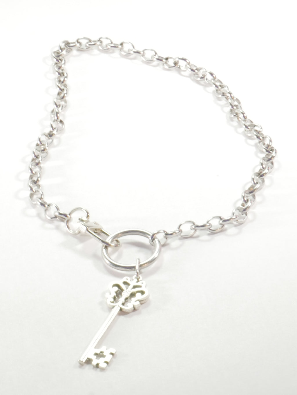 Silver bracelet with a key charm on a white background