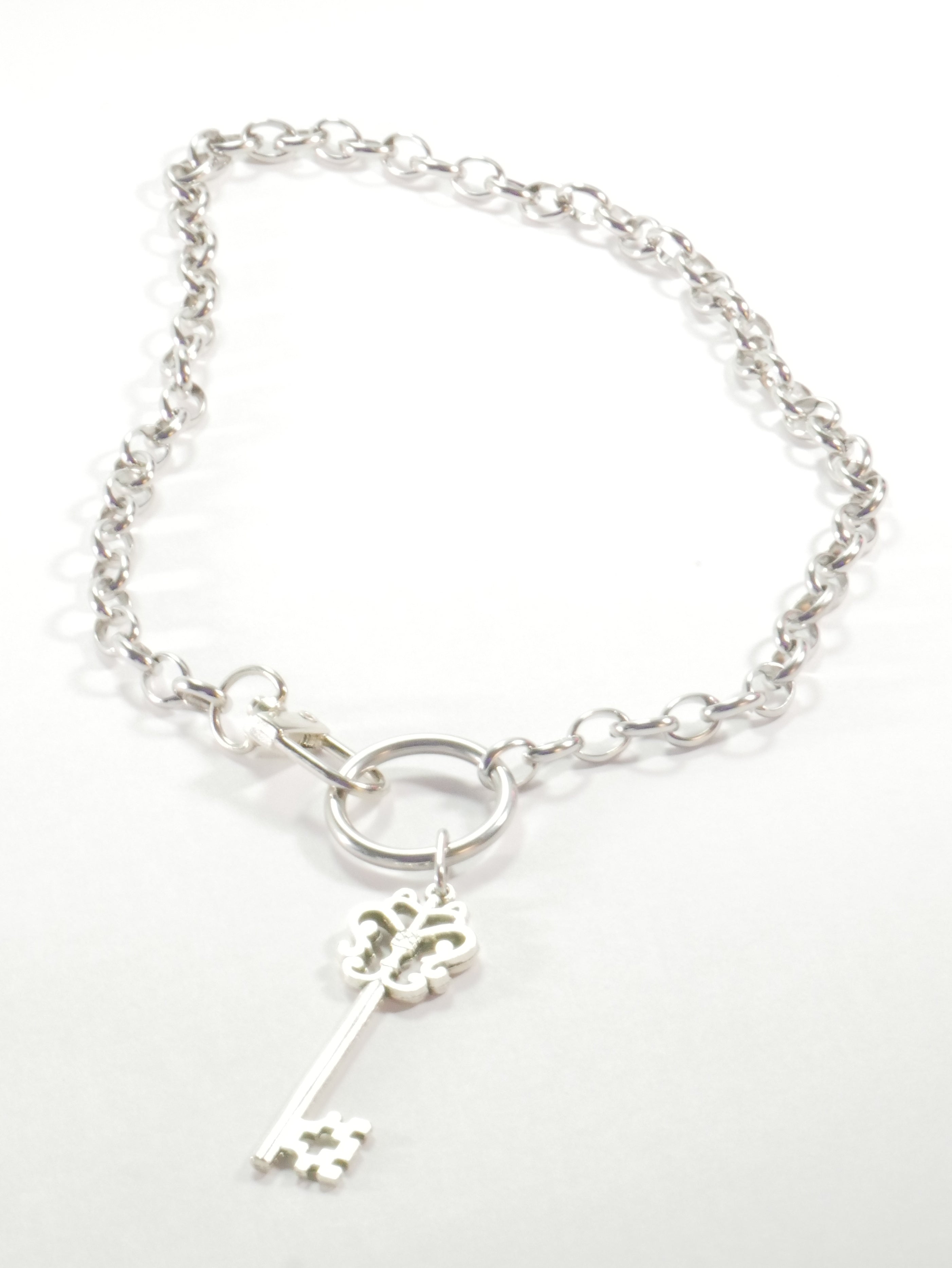 Silver bracelet with a key charm on a white background