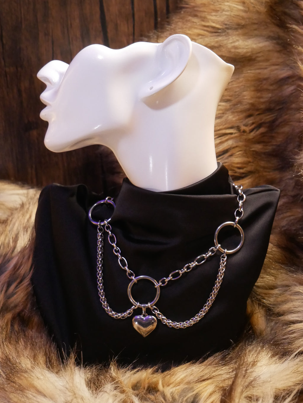 silver chain necklace on a mannequin wearing a black satin top sitting on a brown fur